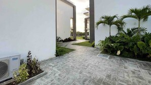 Een modern gebouw met een strak, minimalistisch ontwerp, voorzien van een verhard pad en weelderige beplanting.