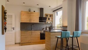 A modern kitchen with wooden cabinets, a black countertop, and a built-in island with bar stools.