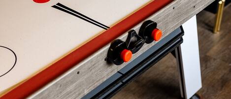 A foosball table with a wooden frame and red accents, positioned on a wooden floor.