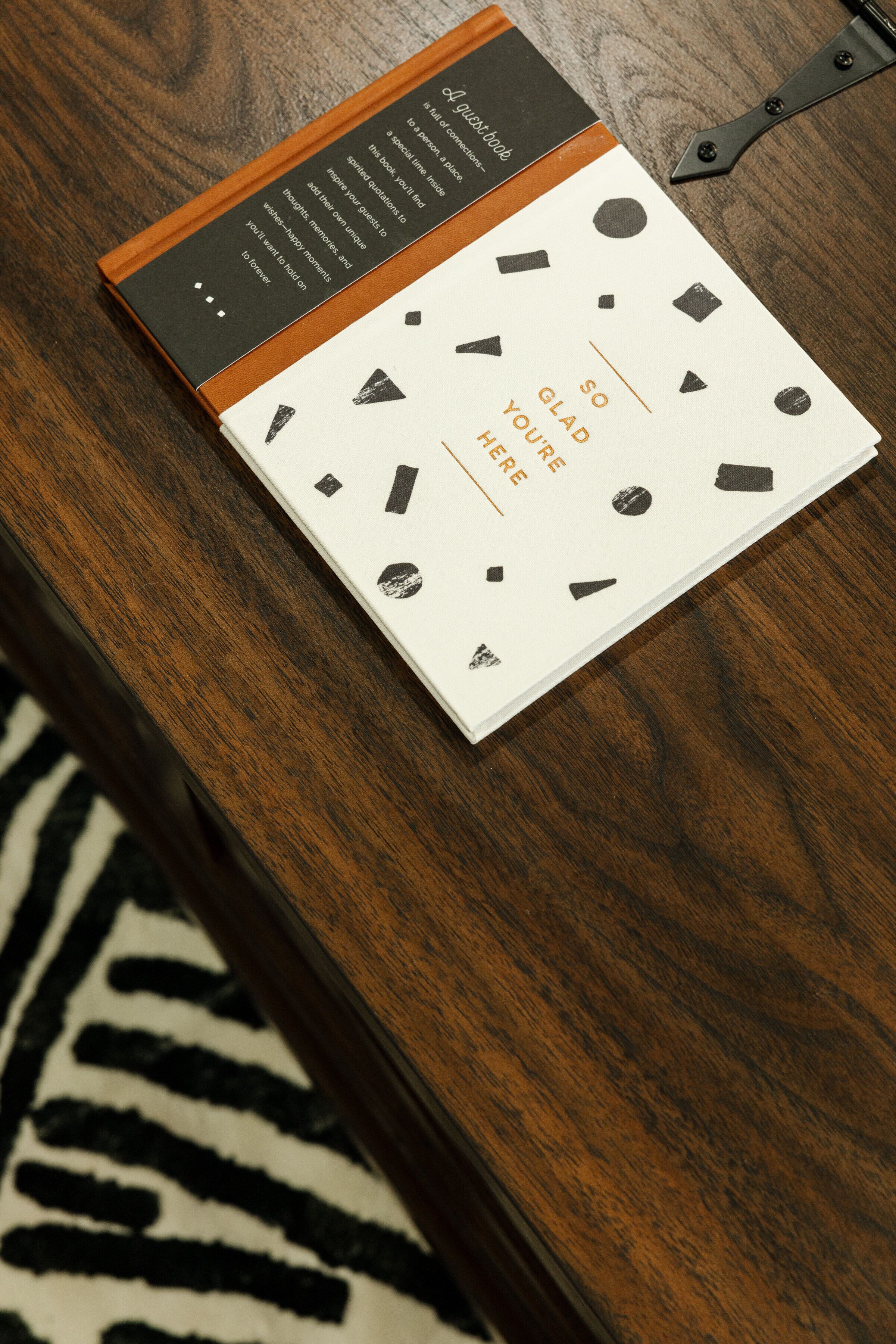 A book with a white cover and black geometric shapes, placed on a wooden surface.