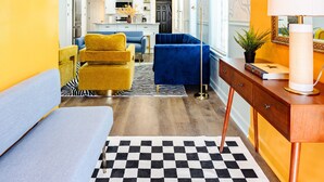 Ein stilvolles Wohnzimmer mit einem Schachbrettmuster-Teppich, einem Sofa und einem blauen Sessel.