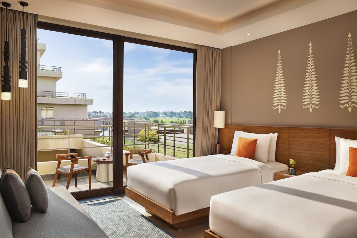 Een hotelkamer met twee bedden, een balkon en uitzicht op de stad.