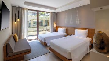 A hotel room with two beds, a sofa, a large window, and a decorative wall piece.