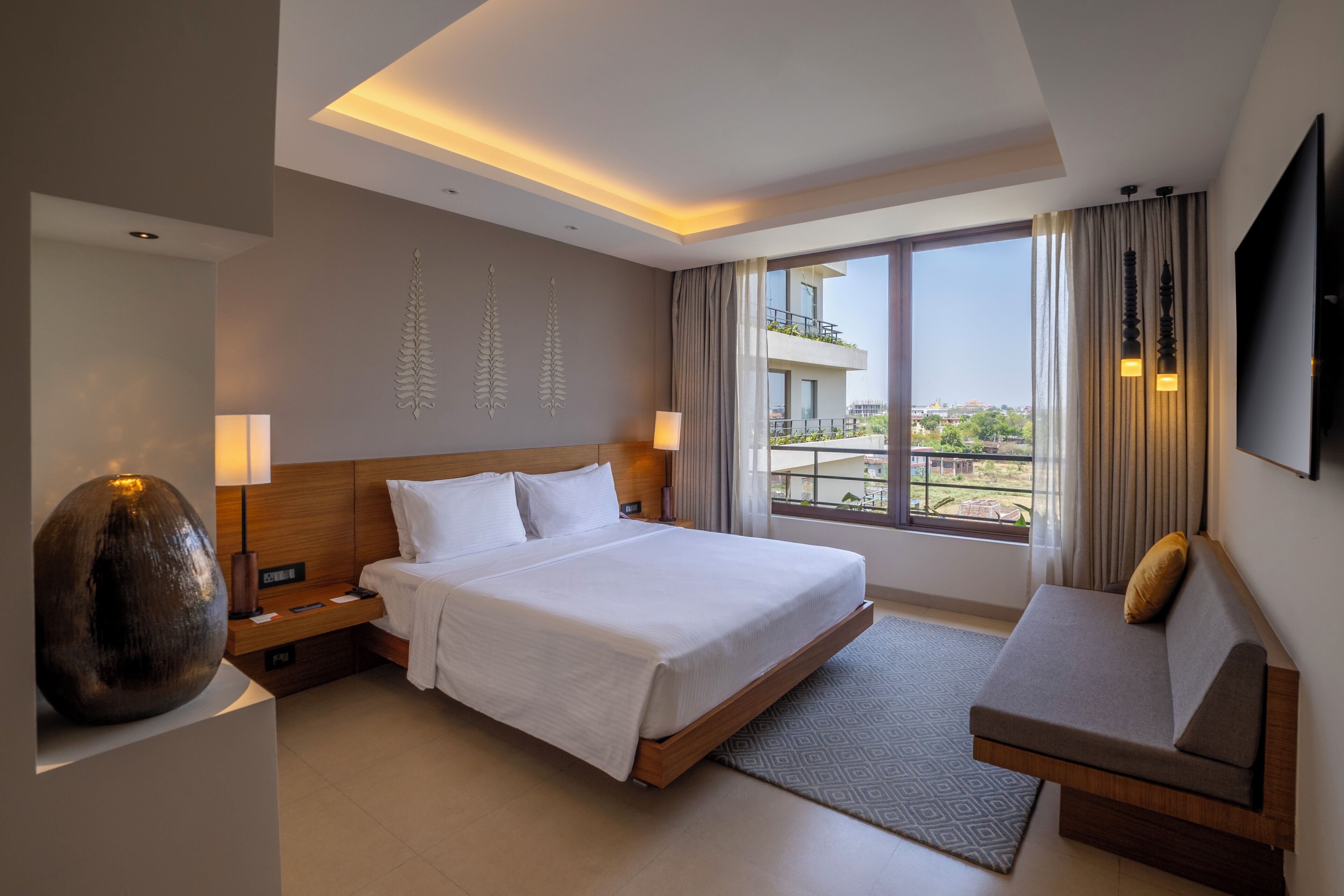 Une chambre d’hôtel moderne avec un grand lit, un canapé, une télévision et une vue sur la ville.