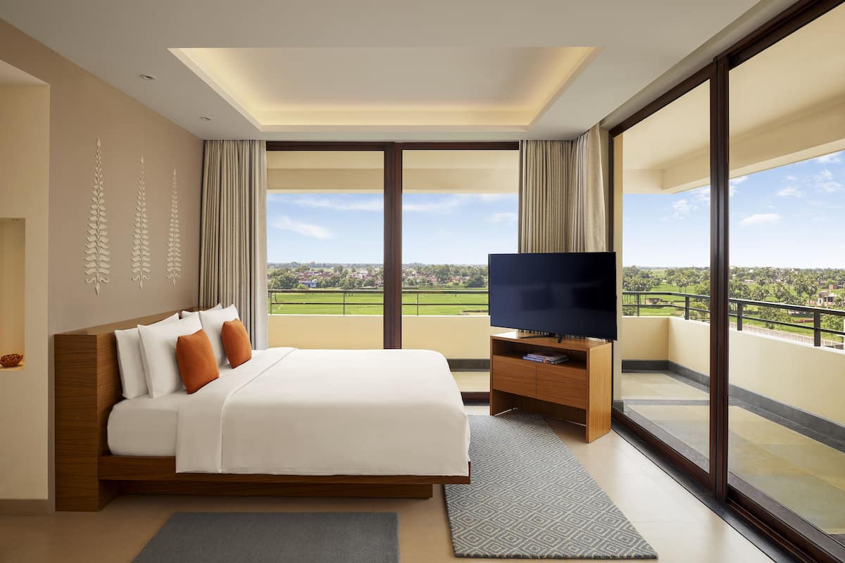 Een moderne hotelkamer met een groot bed, een flatscreen televisie en een balkon met uitzicht over de stad.