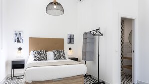 A modern bedroom with a large bed, bedside tables, a floor lamp, and a view of the stairs. - Holidays2Malaga Picassus Lofts (Málaga)