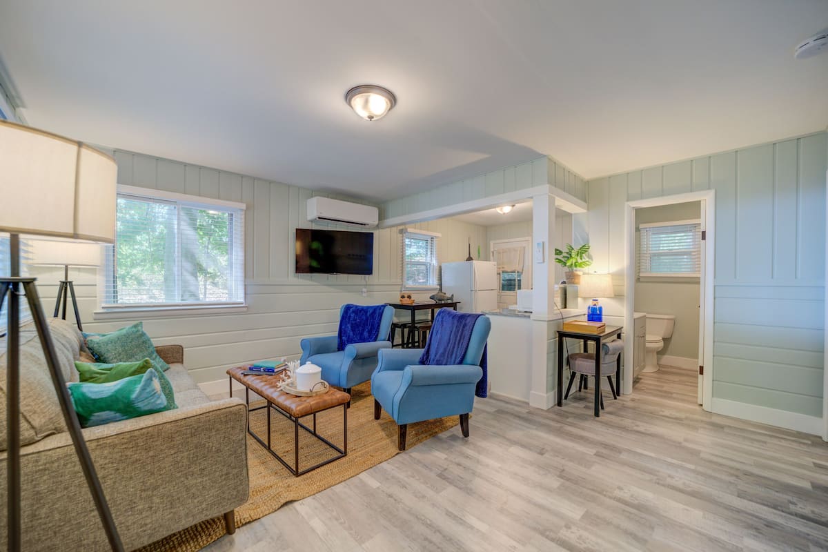 A living room with a sofa, two armchairs, a coffee table, and a dining area with a table and chairs.
