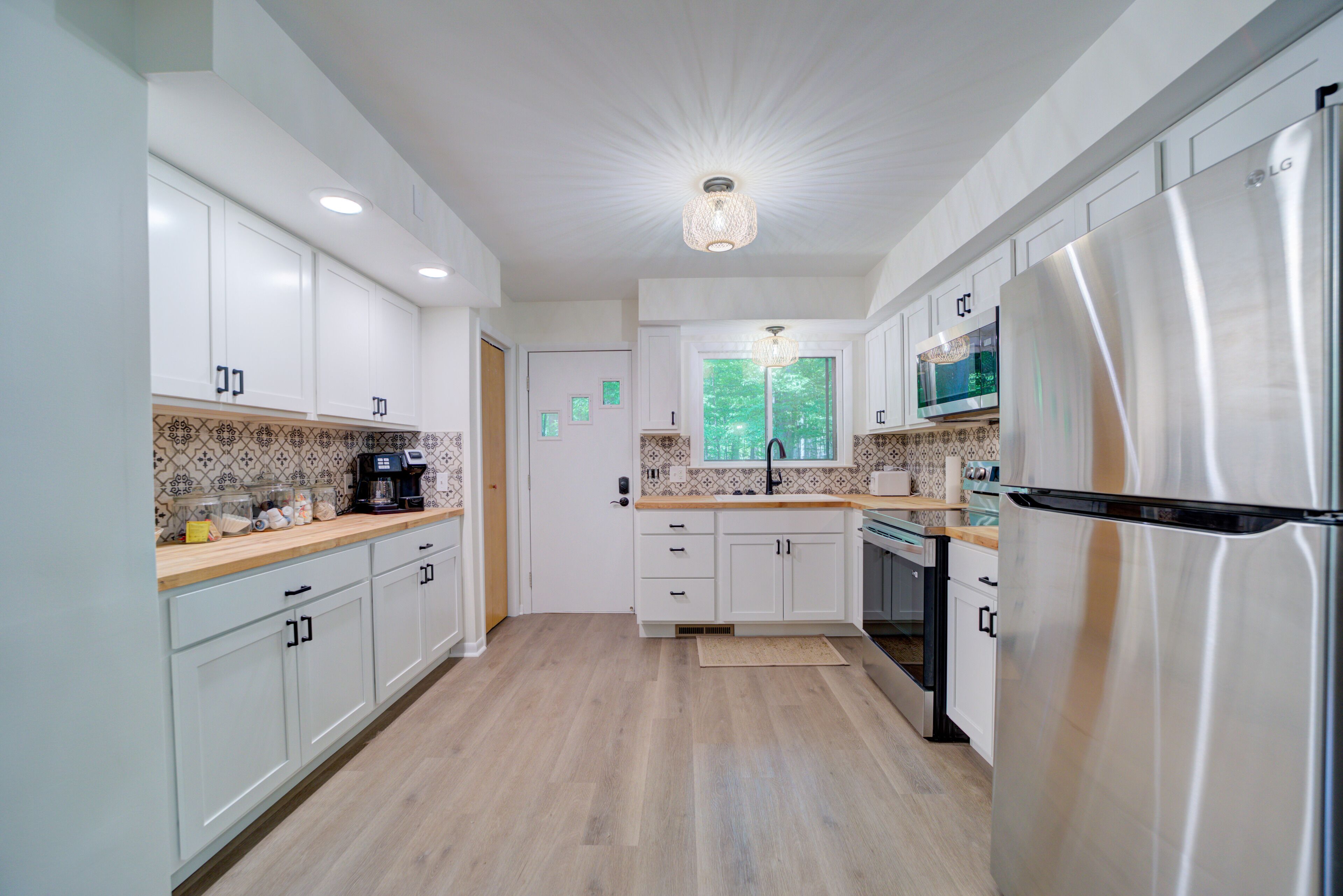 A modern kitchen with white cabinets, a stainless steel refrigerator, and a microwave.