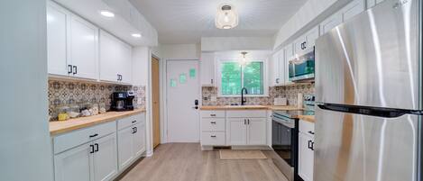 A modern kitchen with white cabinets, a stainless steel refrigerator, and a microwave.