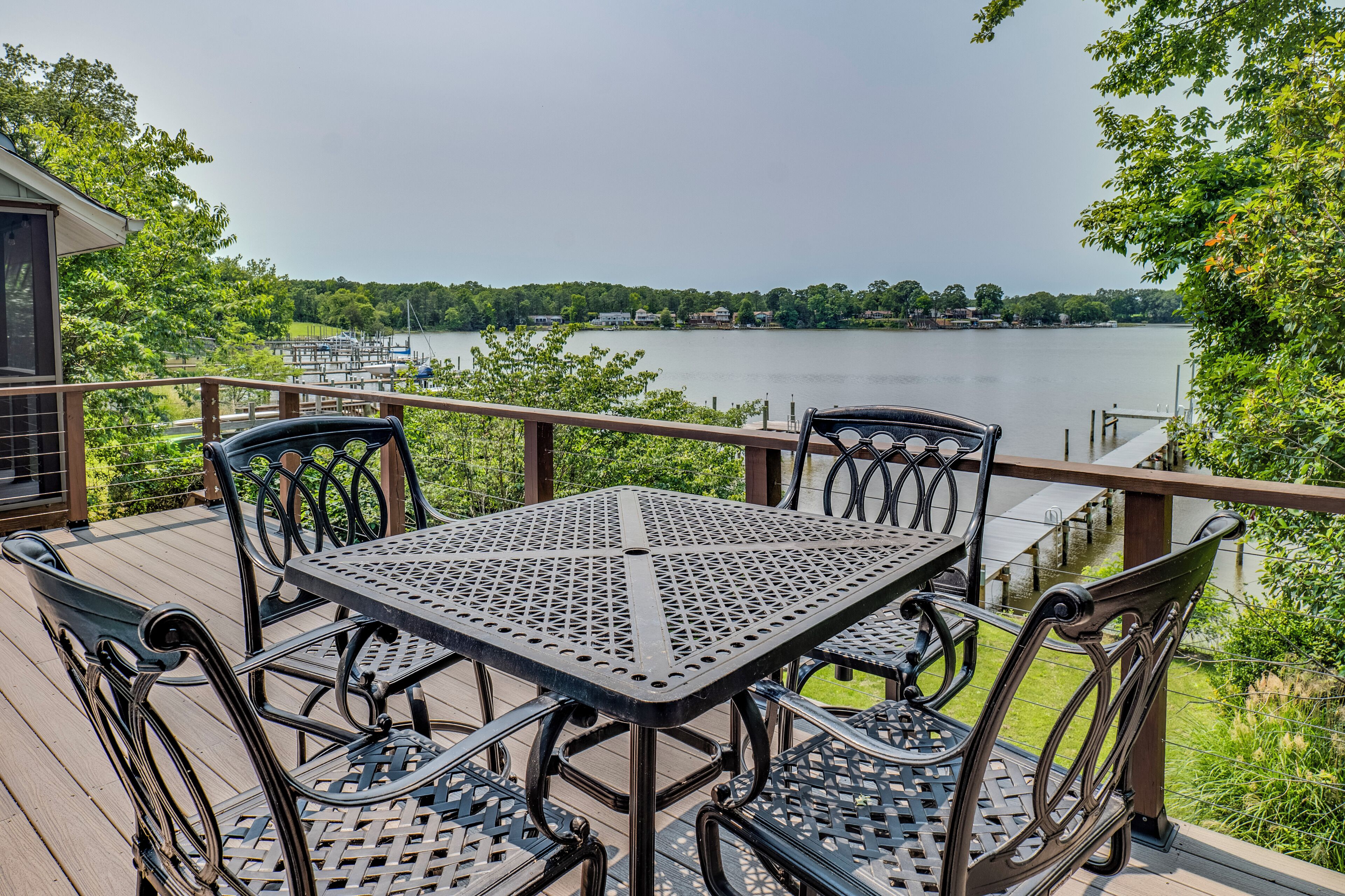 A deck with a table and chairs overlooking a lake.