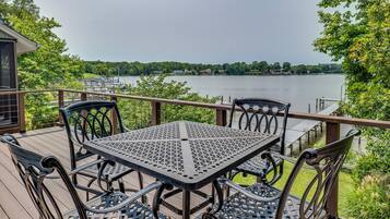 A deck with a table and chairs overlooking a lake.