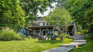 A two-story house with a covered porch, outdoor seating, and a stone pathway leading to the entrance. - River Refresh - Waterfront with Spa on Placid Bay (Colonial Beach)