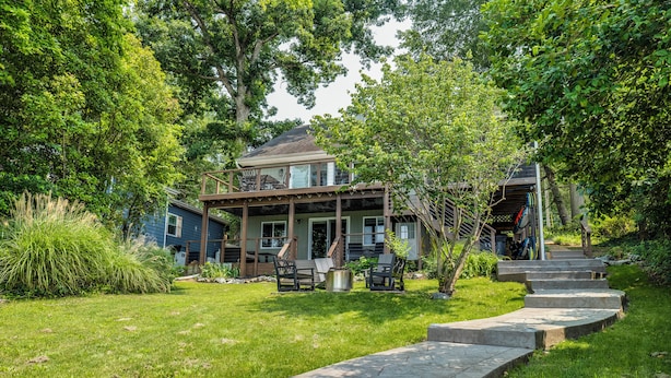 A two-story house with a covered porch, outdoor seating, and a stone pathway leading to the entrance. - River Refresh - Waterfront with Spa on Placid Bay (Colonial Beach)