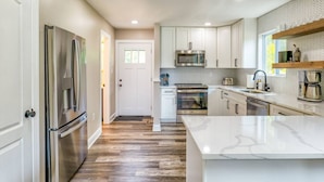 A modern kitchen with stainless steel appliances, white cabinetry, and a herringbone-patterned backsplash. - River Refresh - Waterfront with Spa on Placid Bay (Colonial Beach)