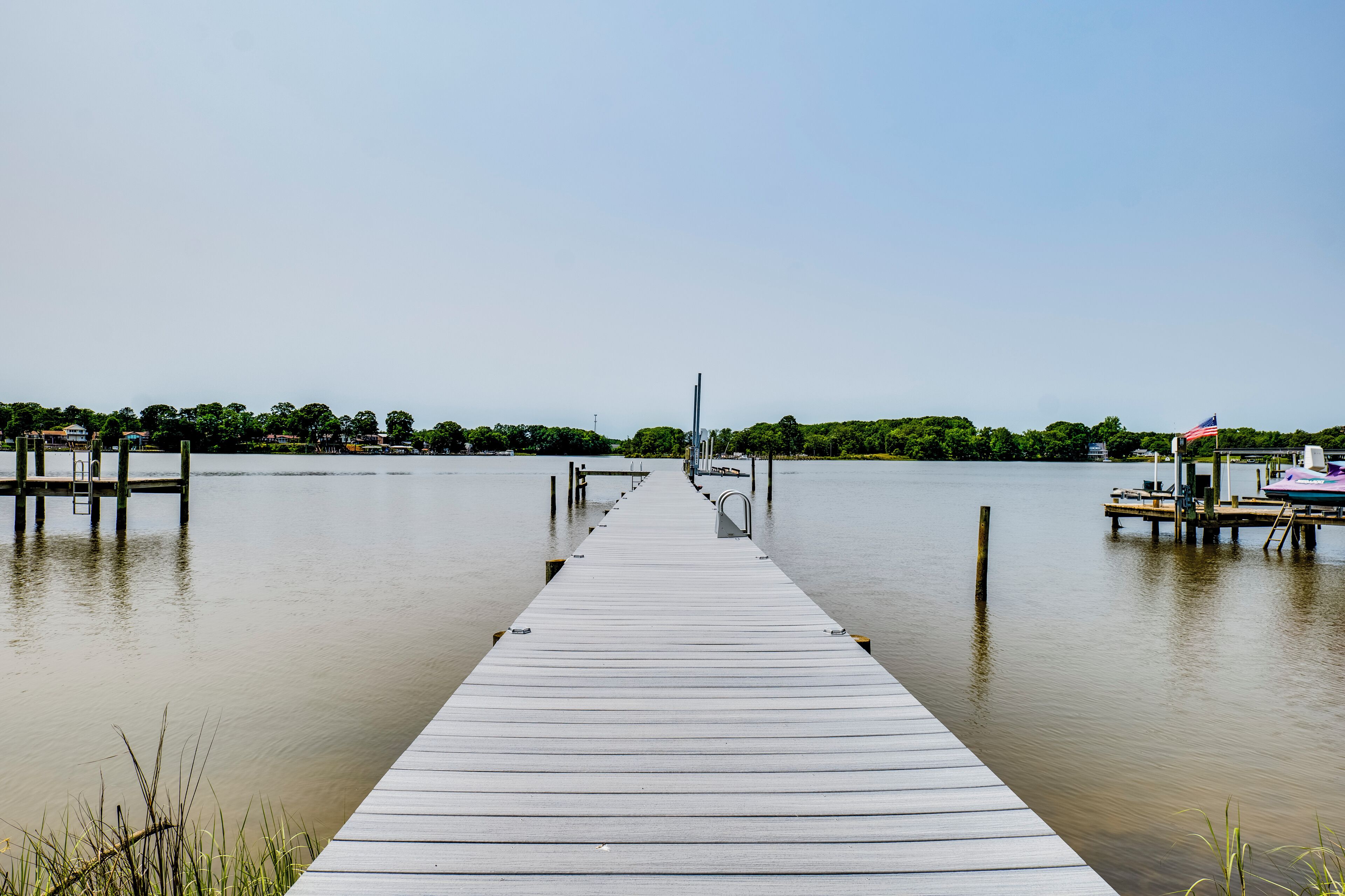A wooden pier extending into calm water with a clear sky above.