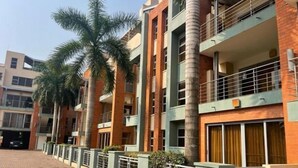 A multi-story residential building with balconies, palm trees, and a brick facade. - Unit 5, Capella Place (East Legon, Accra)