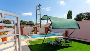 A backyard with a swimming pool, artificial grass, and a covered seating area. - Unit 5, Capella Place (East Legon, Accra)