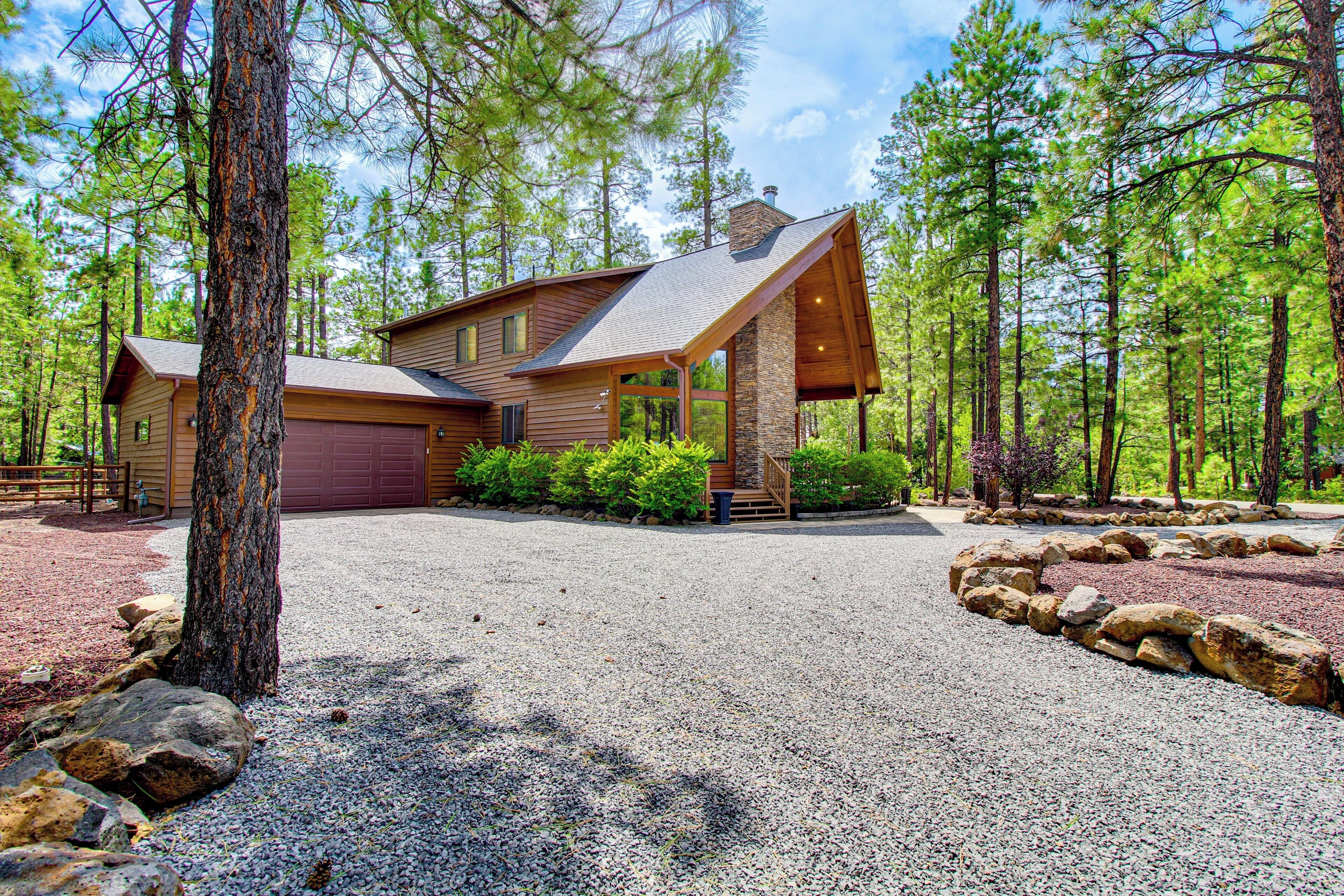 A two-story house with a stone foundation, a large garage, and a gravel driveway.