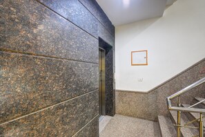 A staircase with granite steps and metal handrails, leading to an elevator. - Qotel Hotel IP Residency  (New Delhi)