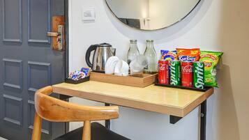 Una pequeña kitchenette con una mesa de madera, una silla, una tetera y diversos aperitivos.
