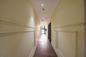 A hallway with a wooden floor and white walls, leading to a door at the end.
