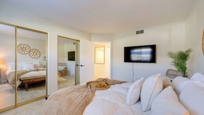 A bedroom with a large bed, a TV mounted on the wall, and a mirror reflecting the room. - Scottsdale Vacation Rental: 1 Mi to Old Town! (Scottsdale)