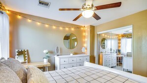 Een slaapkamer met een bed, een dressoir, een kaptafel met spiegel en sfeerverlichting.