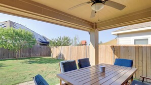A covered patio with a wooden table and chairs, a ceiling fan, and a view of a backyard with a wooden fence and trees. - 6 Mi to Dtwn Mansfield! Family Getaway w/ Patio (Mansfield)