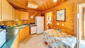 A wooden cabin interior with a kitchen, dining area, and a bathroom visible through an open door. - Lakefront Wisconsin Escape w/ Boat Dock & Kayaks! (Oconomowoc)