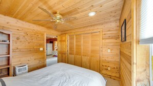 A wooden-paneled room with a bed, a ceiling fan, and a window. - Lakefront Wisconsin Escape w/ Boat Dock & Kayaks! (Oconomowoc)