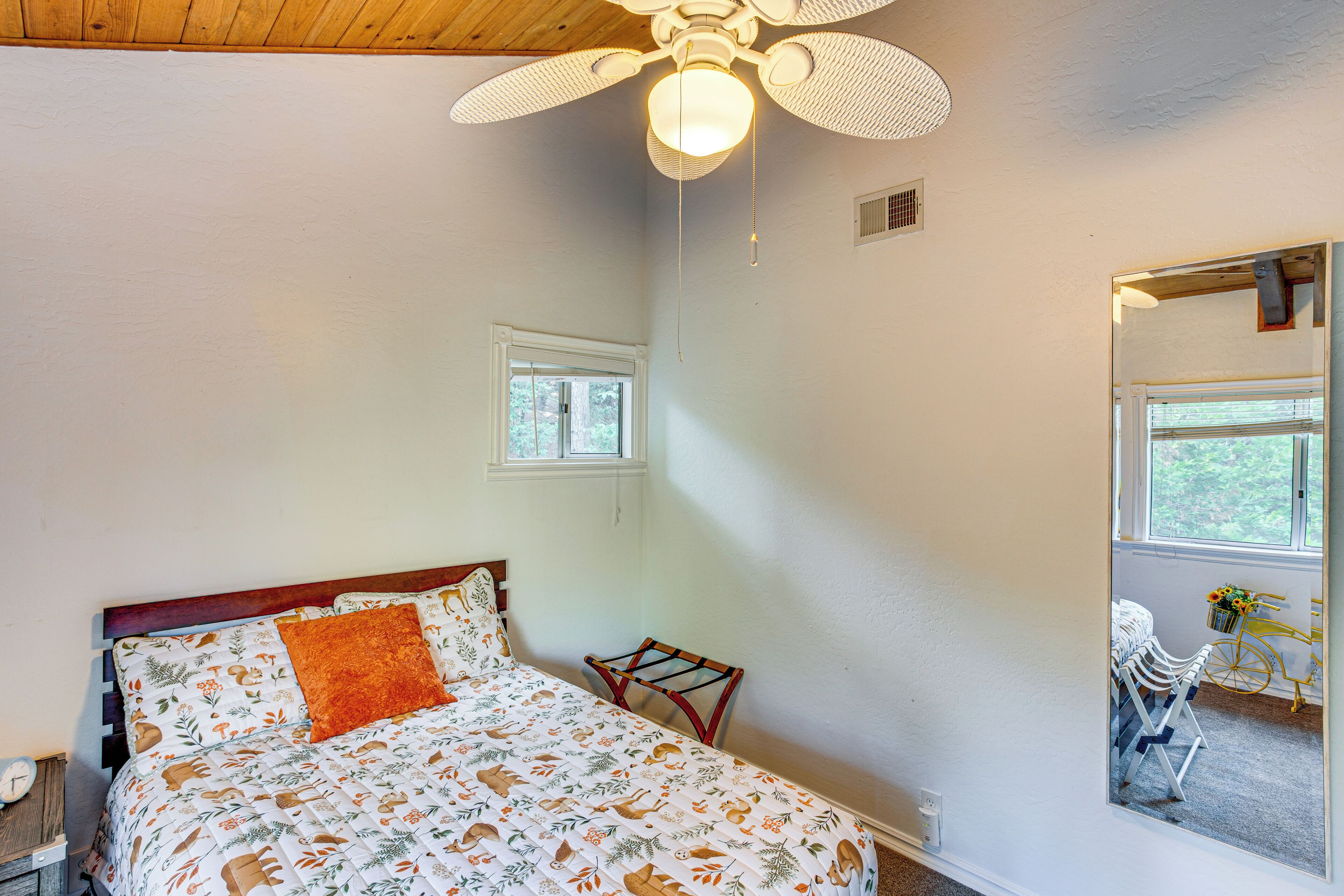 A bedroom with a bed, a ceiling fan, a window, and a chair by the window.