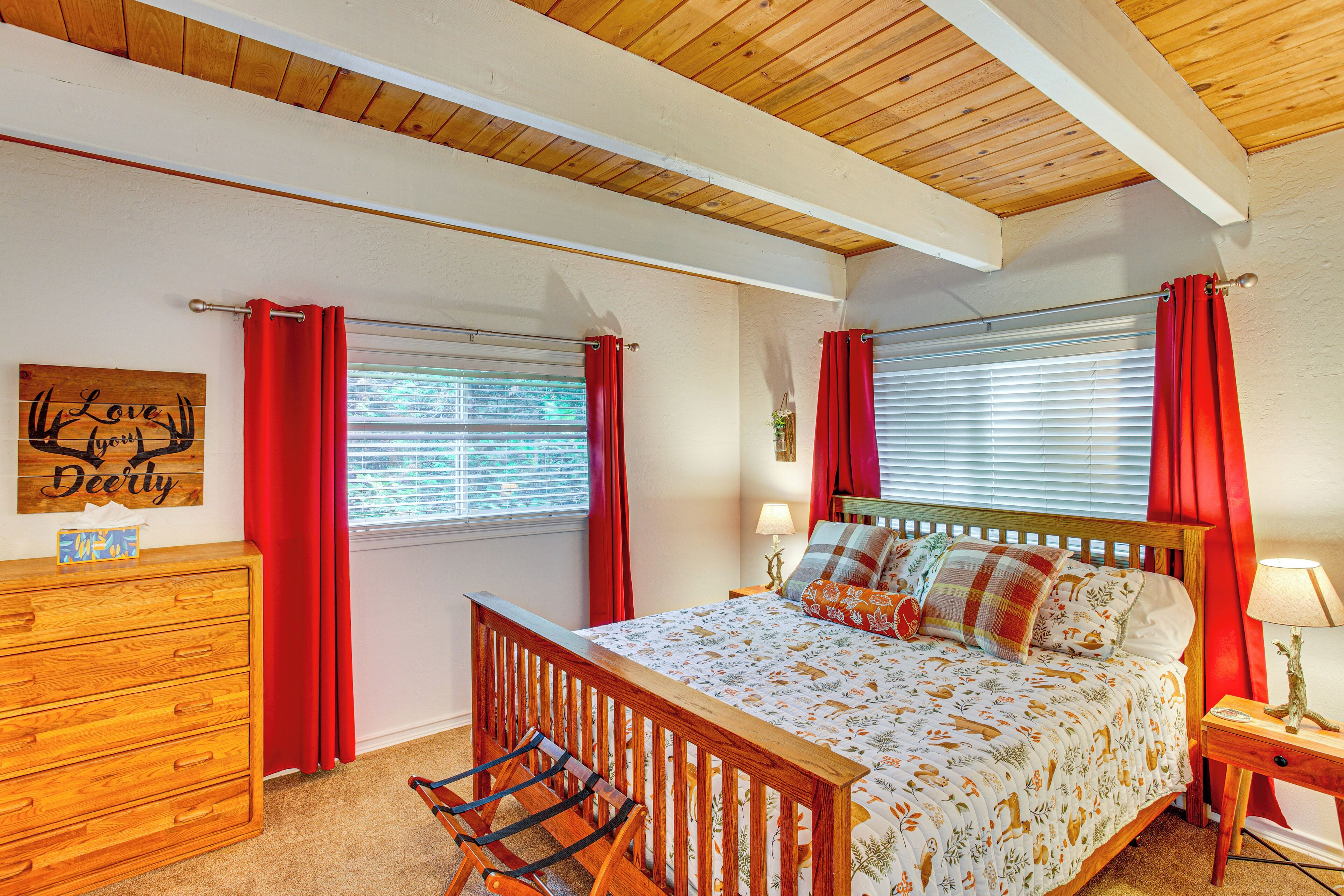 Une chambre à coucher avec un lit en bois, une table de chevet avec une lampe, une commode et une fenêtre avec des rideaux rouges.