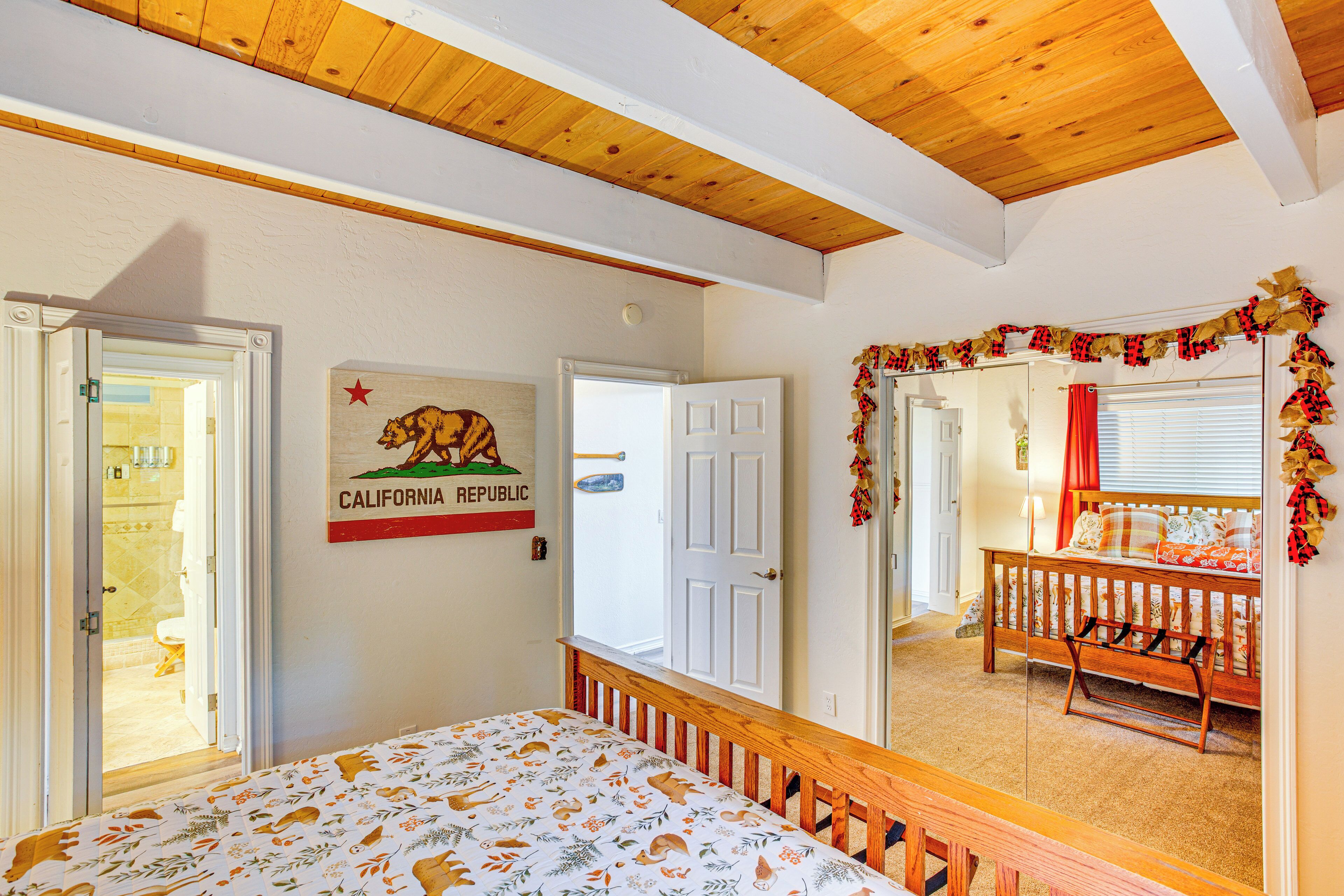 A bedroom with a bed, a door, a wall with a bear illustration, and a window with curtains.