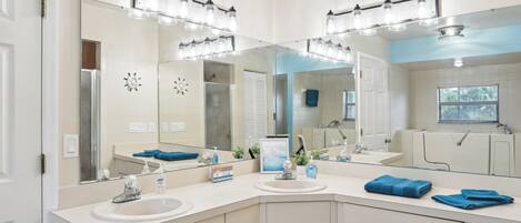 A bathroom with a large mirror, vanity, and a sink.