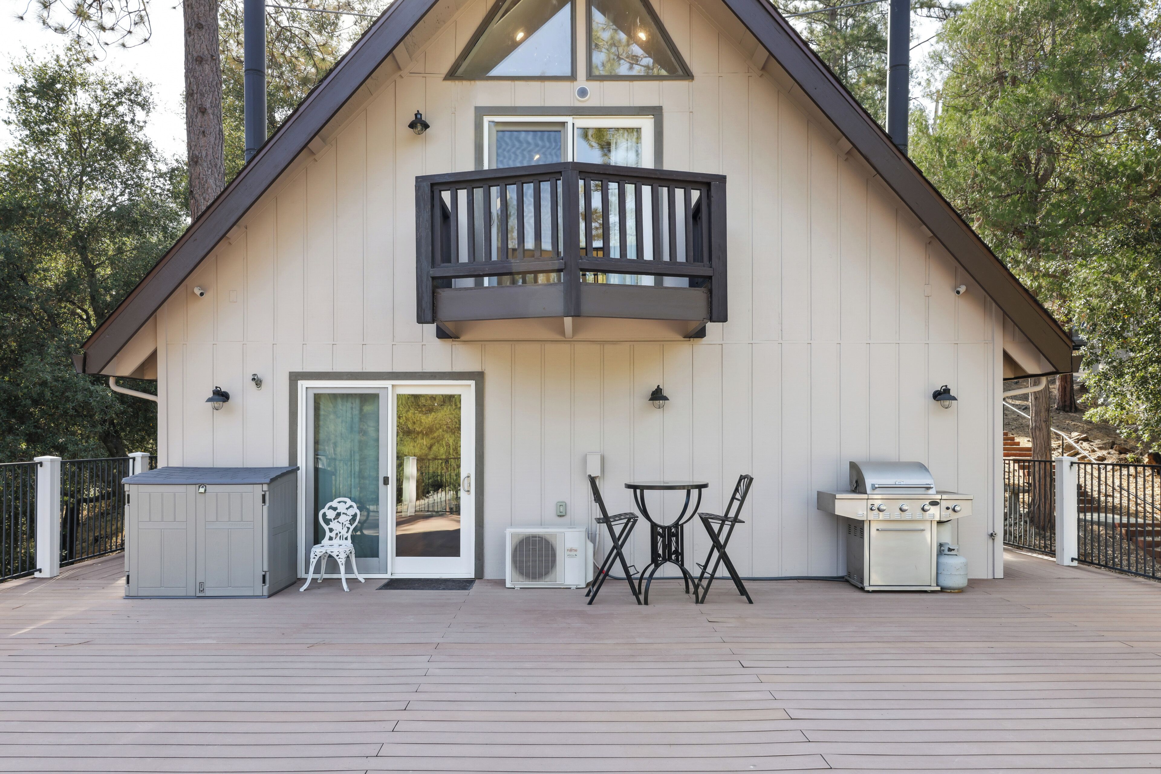 Ein modernes Haus mit Balkon, Grill und einem kleinen Tisch mit St ühlen.