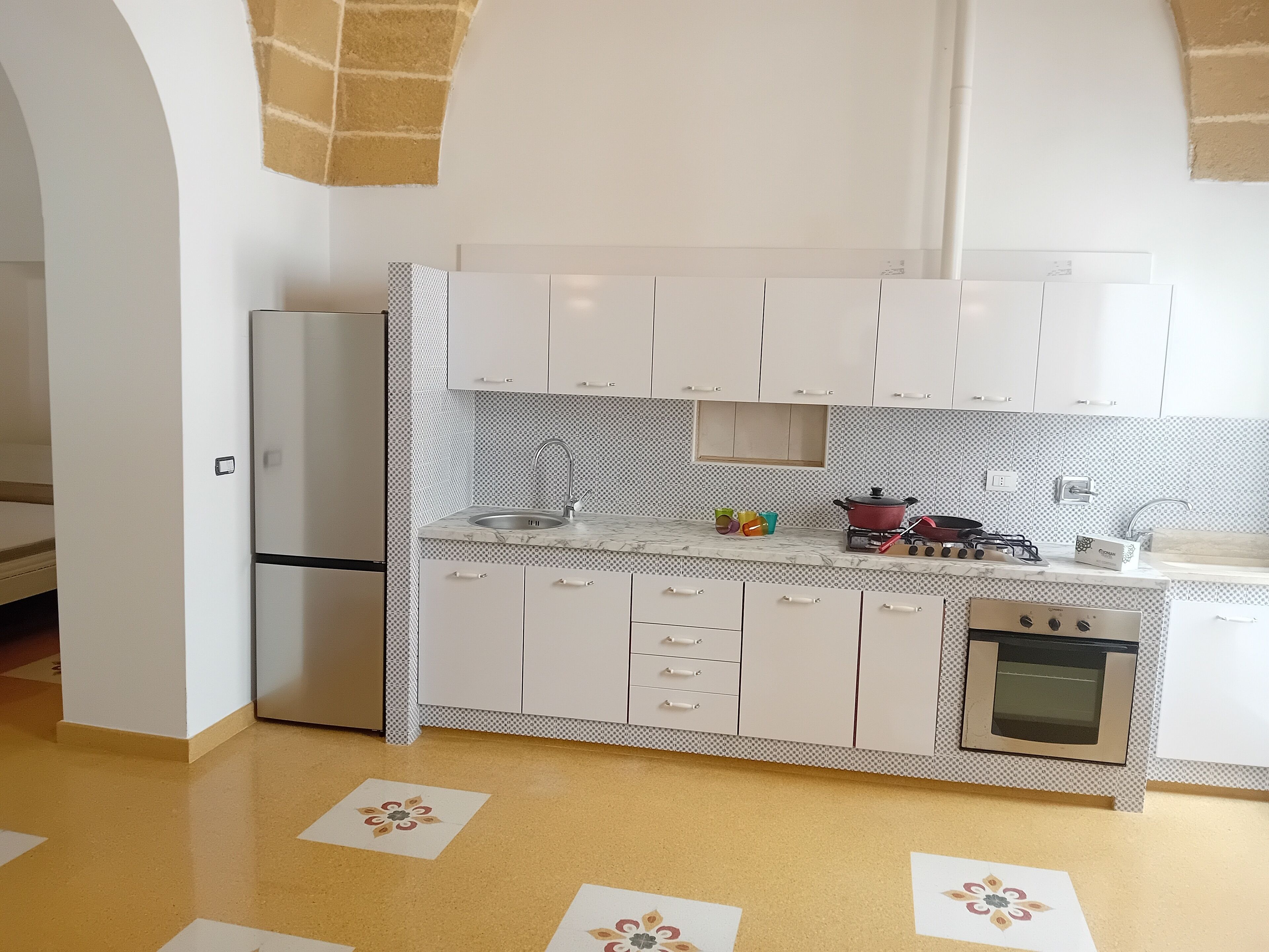 A modern kitchen with white cabinets, a built-in oven, and a sink.