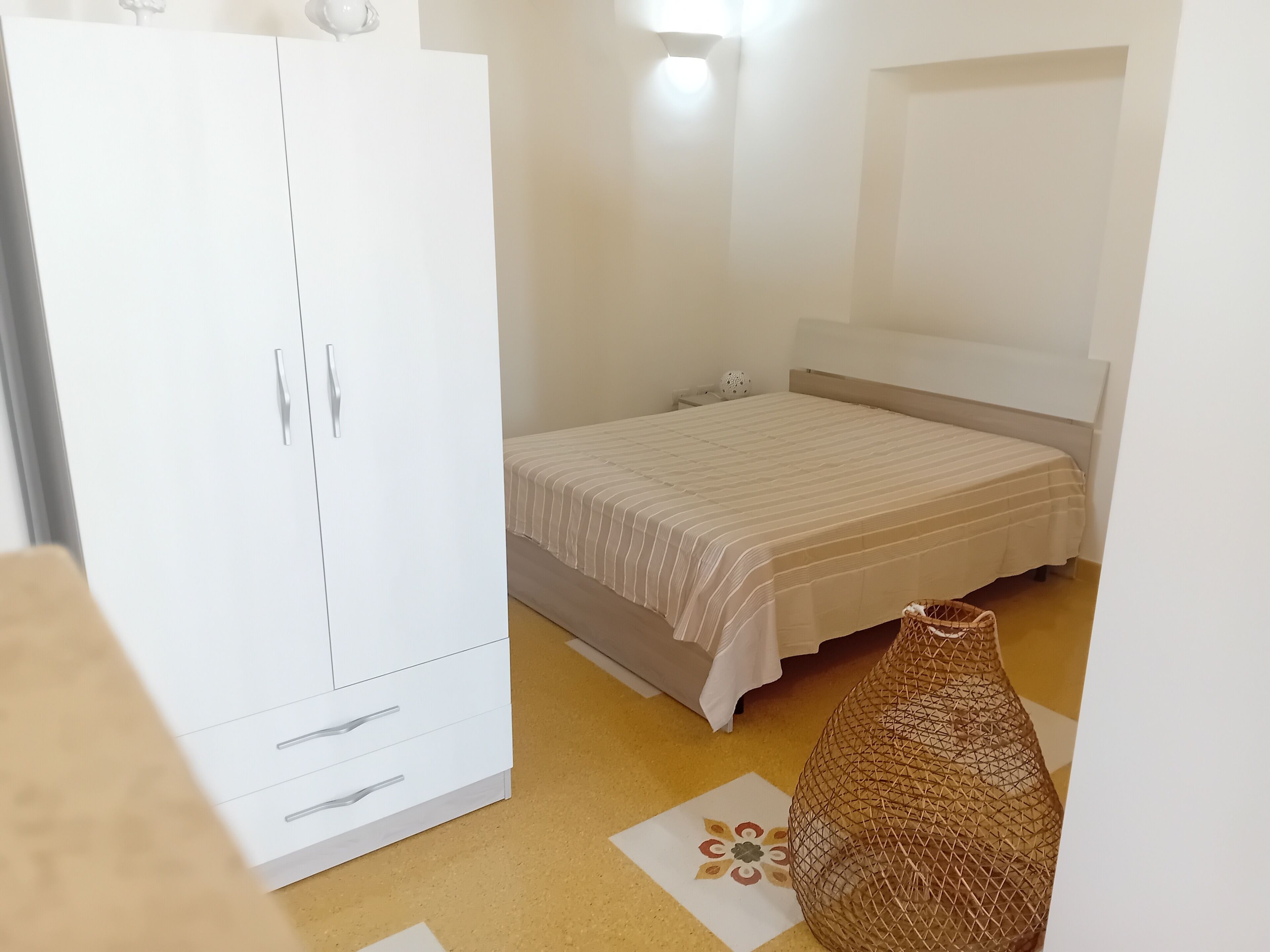 A bedroom with a bed, a wardrobe, and a decorative basket.