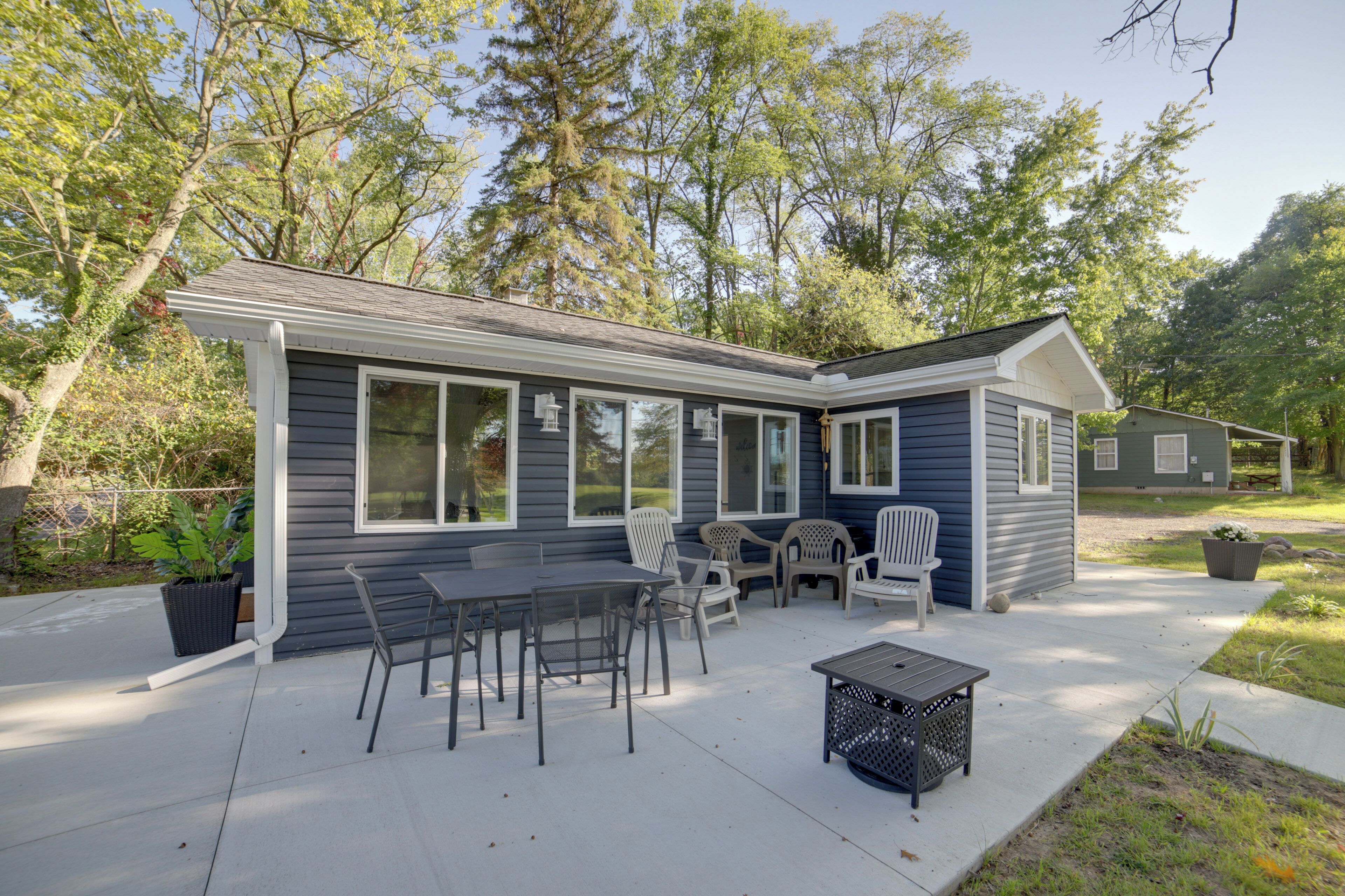 A house with a patio area featuring a table and chairs, surrounded by trees.