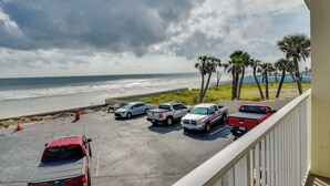 A parking area with several vehicles, a beach, and palm trees in the background. - Cozy Florida Getaway w/ Pool Access & Ocean Views! (Daytona Beach)