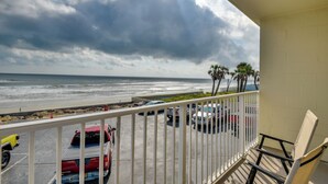 A balcony with a view of the beach and ocean, featuring parked cars and palm trees. - Cozy Florida Getaway w/ Pool Access & Ocean Views! (Daytona Beach)