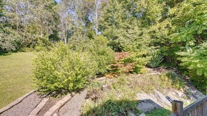 A landscaped garden with various plants and trees, a stone pathway, and a wooden fence.