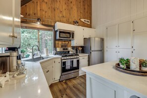 Una cocina moderna con electrodomésticos de acero inoxidable, detalles de madera y vistas al exterior.