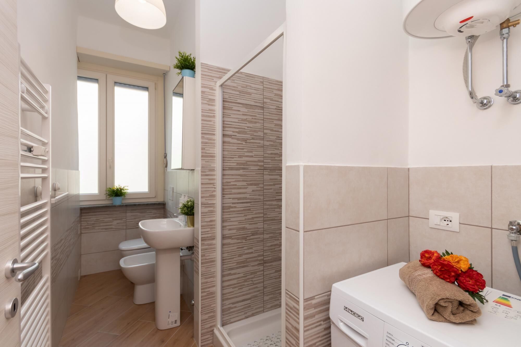 A modern bathroom with a shower, toilet, sink, and a towel with flowers on the counter.