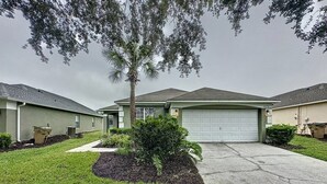 A residential house with a garage, a lawn, and a palm tree. - 4 Bed 3 Bath In A Gated Community With Pool 4 Bedroom Villa by RedAwning (Kissimmee)