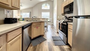 A kitchen with wooden cabinets, stainless steel appliances, and a large island with a dishwasher. - 4 Bed 3 Bath In A Gated Community With Pool 4 Bedroom Villa by RedAwning (Kissimmee)