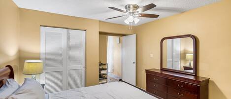 Ein Schlafzimmer mit Bett, Schminktisch, Deckenventilator und Spiegel.
