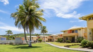 Un resort con varias edificaciones de dos pisos, un césped bien cuidado y palmeras.
