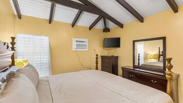 A bedroom with a bed, dresser, TV, and a ceiling fan.