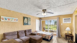 Una camera accogliente con divano, letto, ventola a soffitto e vista su un giardino dalla finestra.