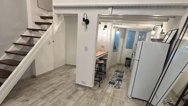 A compact living space with a staircase leading to a loft area, a kitchenette, and a dining area.